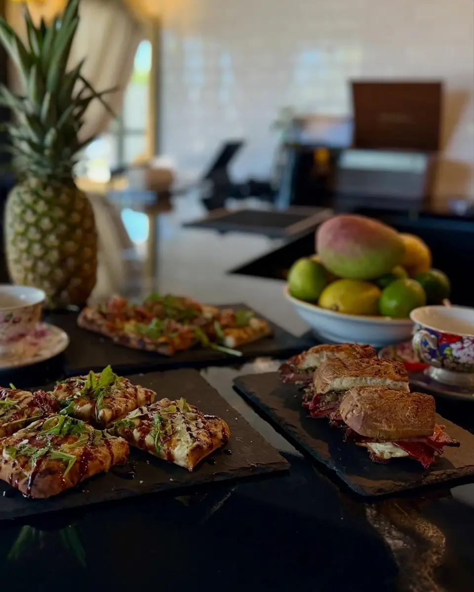 A brunch spread on the bar: flatbreads, sandwiches and a bowl of fruit with a pineapple